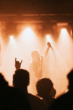 a person standing in front of a microphone on top of a stage with spotlights