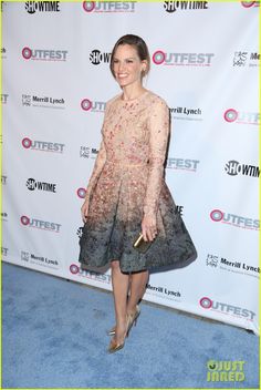 a woman in a dress and heels standing on a blue carpet with a white background
