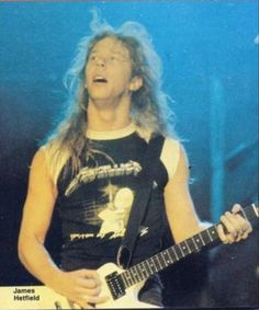 a man with long hair playing an electric guitar