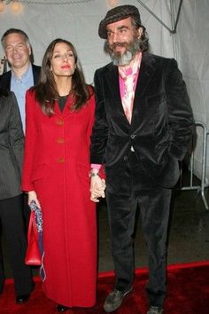 three people standing next to each other in front of a white tent with red carpet
