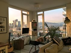 a living room filled with furniture and lots of windows overlooking the cityscape in the distance