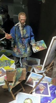 a man standing in front of a pile of paintings