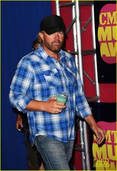 a man in plaid shirt holding a drink