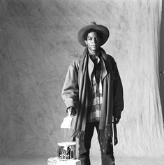 a black and white photo of a man in a cowboy hat holding a birdcage
