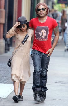 the man and woman are walking down the street together, one is wearing a hat