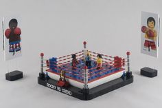 a toy boxing ring with two small figurines on each side and an action figure in the middle