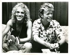 two women sitting on a couch with guitars in their hands and smiling at the camera