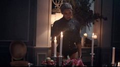 a woman is standing in front of candles
