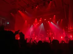 a group of people that are standing in front of some red lights at a concert