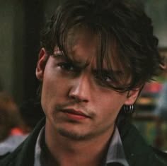 a close up of a young man wearing earring's and looking at the camera