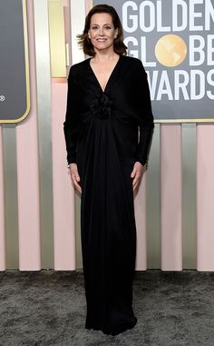 a woman in a black dress posing for the camera at an awards event with her hands on her hips
