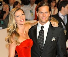a woman in a red dress and a man in a black suit posing for the camera