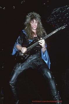 a man with long hair playing an electric guitar