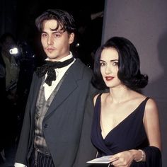 a man in a tuxedo standing next to a woman