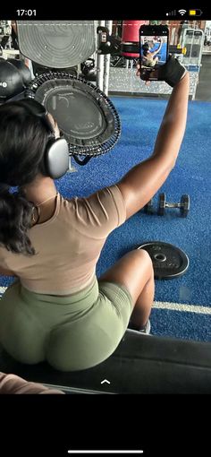 a woman sitting on the ground with headphones in her ears and holding a cell phone up to her ear