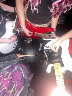three people are playing guitars in a room