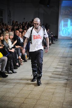 a man walking down a runway with lots of people watching him on the other side