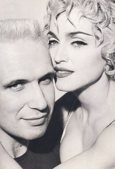 a black and white photo of a man and a woman posing for the camera with their arms around each other