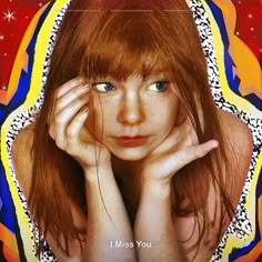 a girl with red hair and blue eyes is looking at the camera while holding her hands to her face