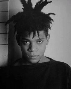 a black and white photo of a young man with dreadlocks on his head