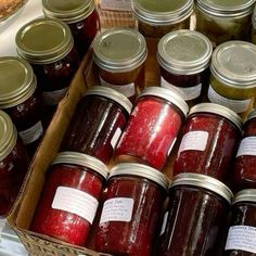 many jars of jam are stacked on top of each other in a box with labels