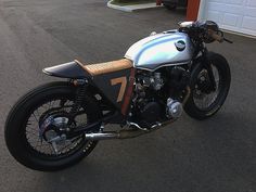 a silver motorcycle parked in front of a garage with a red and black stripe on it