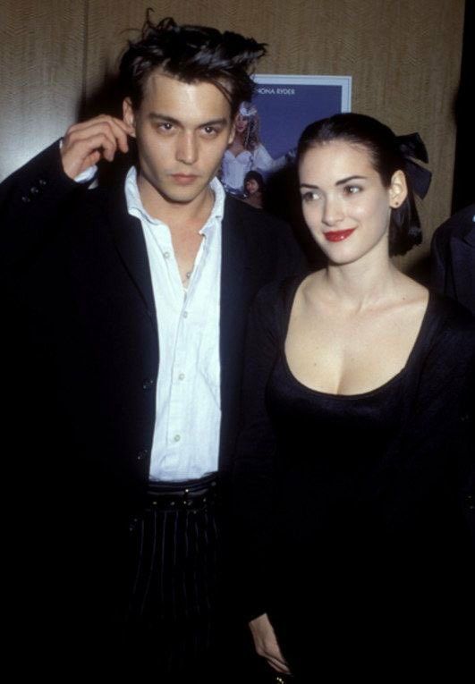 a man and woman standing next to each other in front of a poster on the wall