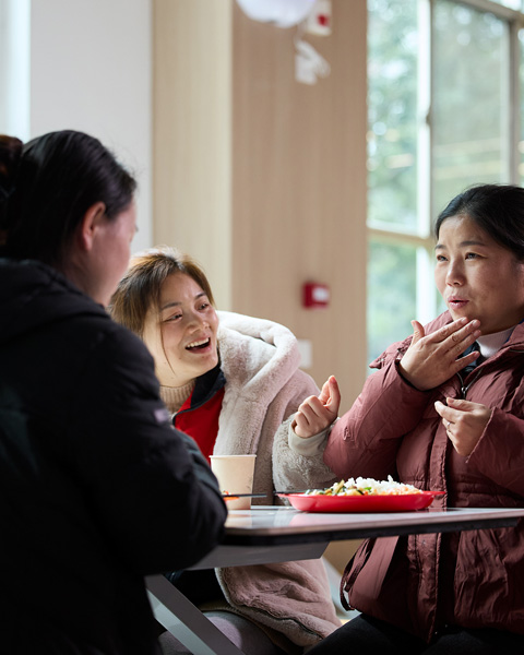 Three people sitting at a table in a restaurant, communicate in sign language with each other